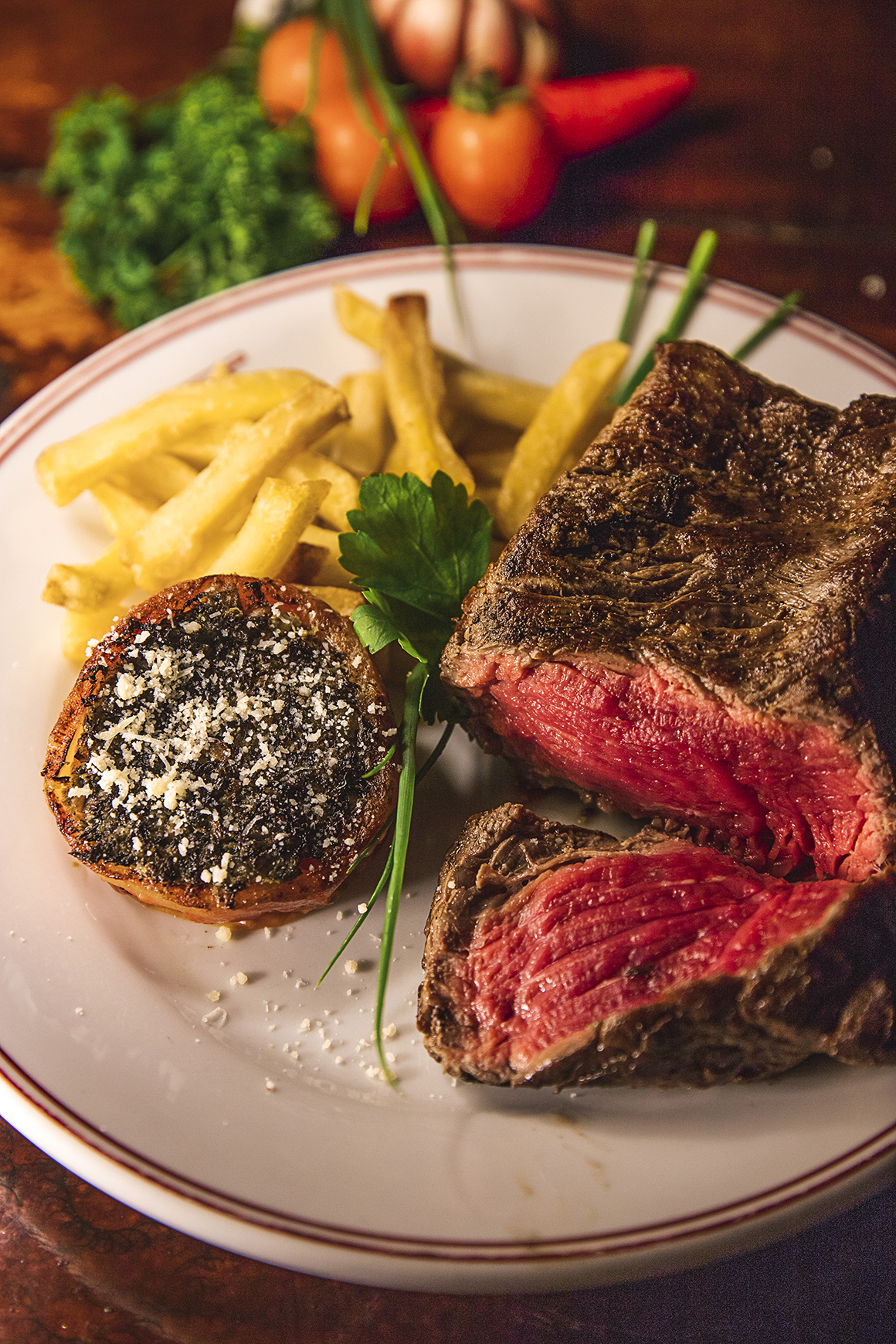 Na foto um corte de carne vermelha e porção de batatas fritas.